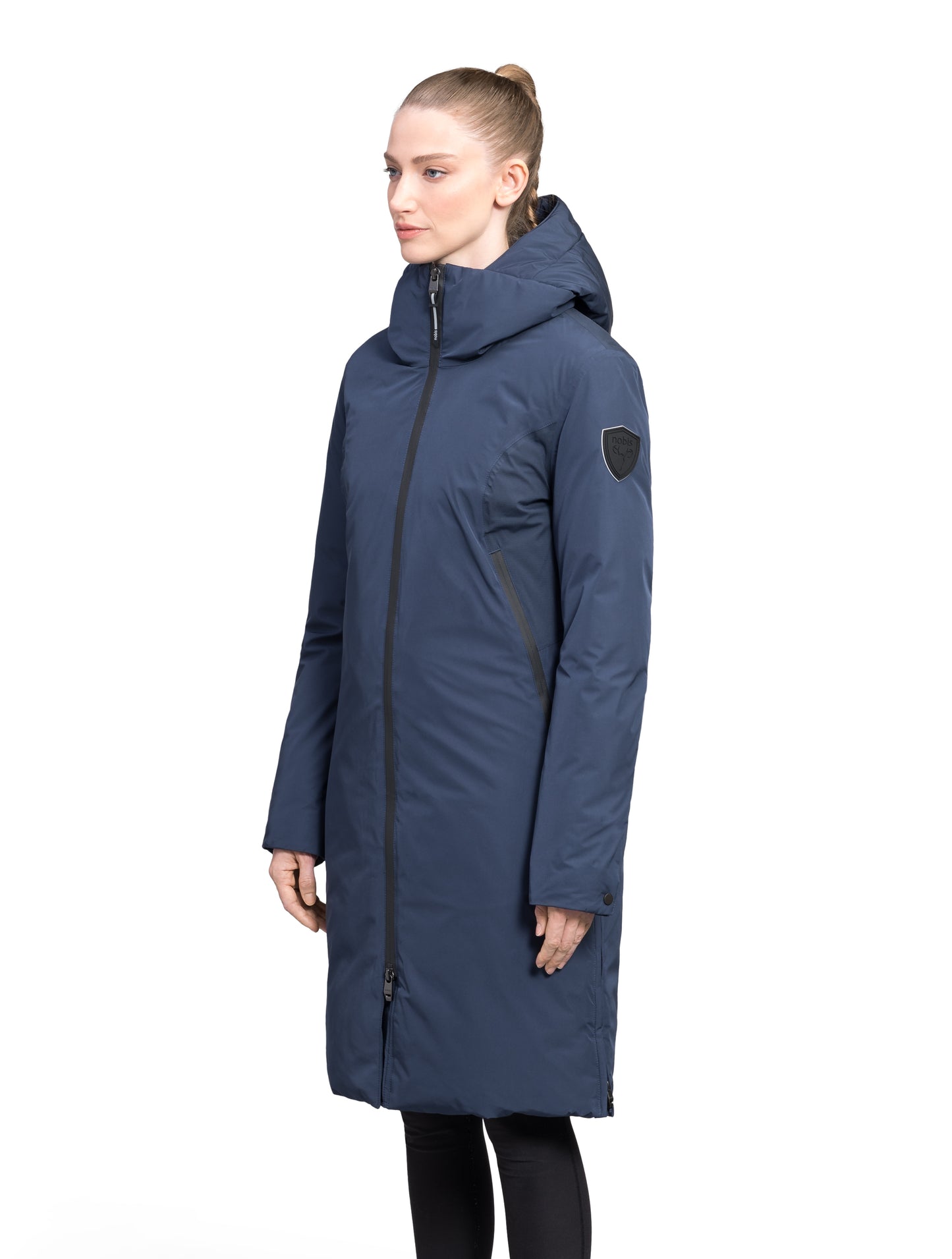 Inara Women's Performance Parka in knee length, premium 3-ply micro denier and stretch ripstop fabrication with DWR coating, Premium Canadian White Duck Down insulation, non-removable down-filled hood, centre front two-way zipper, large vertical zipper pockets along waist, zipper vents along bottom side hem, in Marine