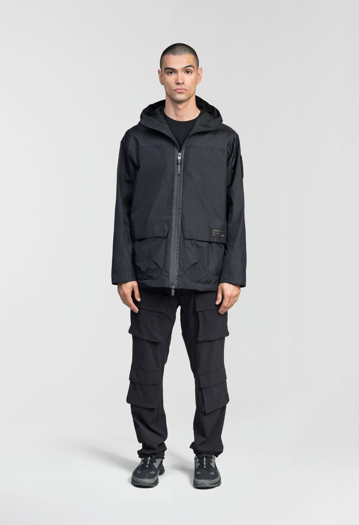Mission Men's Performance Rain Shell Jacket in hip length, non-removable hood with adjustable toggle, two-way waterproof zipper, flap closure waist pockets with additional side entry storage, zipper ventilation on back, passive underarm ventilation, and breathable mesh lining, in Black