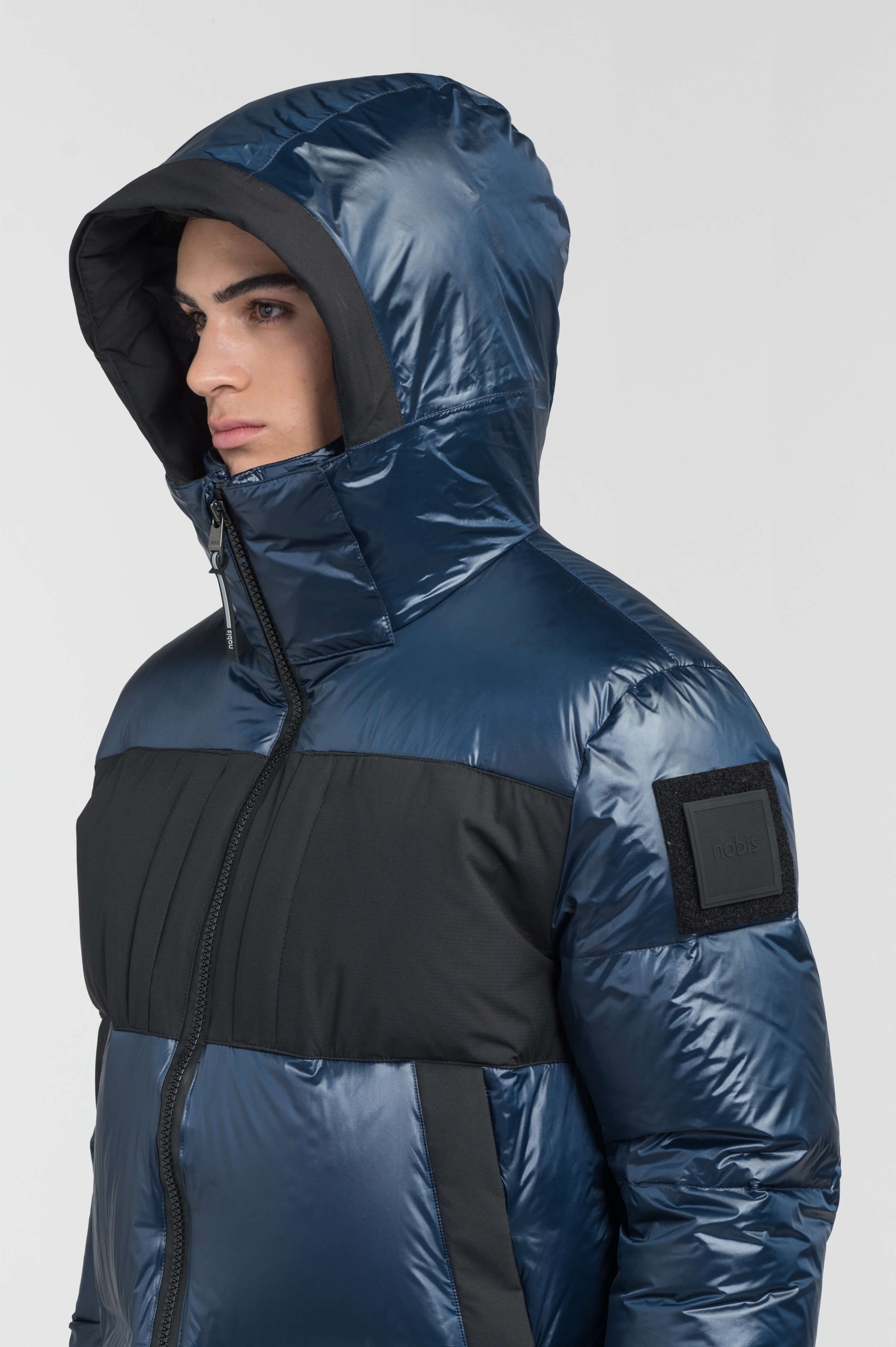 Neelix Men's Long Puffer Jacket in thigh length, premium cire technical nylon taffeta and stretch ripstop fabrication, Premium Canadian origin White Duck Down insulation, non-removable down-filled hood, two-way centre-front zipper, pit zipper vents, hidden chest zipper pockets, fleece-lined magnetic closure waist pockets, in Marine